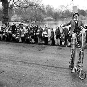 A clown stilt walker seen here riding a oversize bicycle in the Easter parade