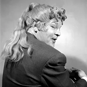Comedian Benny Hill pictured at home wearing a wig May 1958
