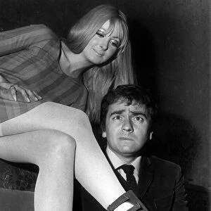 Comedian Dudley Moore pulling a face inspects a pair of boots called "Sex Puss"