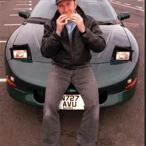 COMEDIAN Fred MacAulay WITH SUPER CAR TRANS AM EATING A HAMBURGER COMEDIAN Fred MacAulay WITH SUPER CAR TRANS AM EATING A HAMBURGER