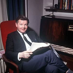 The comic actor Benny Hill in his Kensington flat reading February 1966 in his armchair