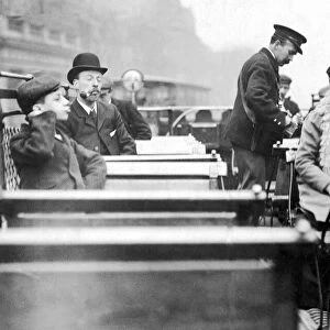 A conductor checks for passengers tickets on the open top deck of a London tram