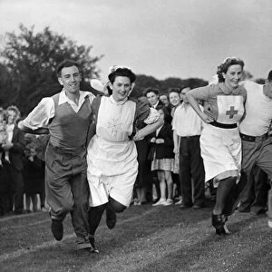 Convalescent soldiers run a three legged race with their nurses at a village sports day