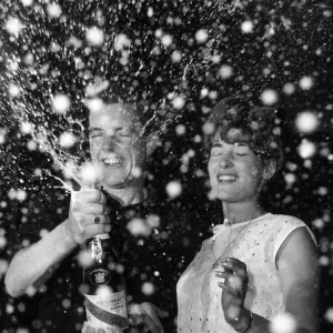 Couple celebrate the new year with a bottle of champagne 1st January 1965