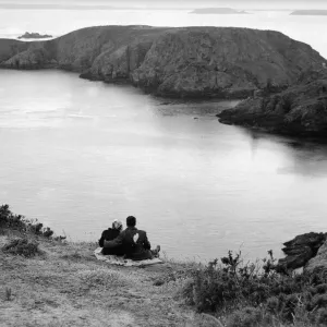 A couple enjoy some time together looking out across the sea on the Channel Island of A couple enjoy some time together looking out across the sea on the Channel Island of