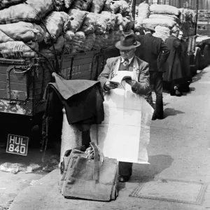 Covent Garden Market stall vendor stops to read a magazine. Circa 1955 Covent Garden Market stall vendor stops to read a magazine. Circa 1955