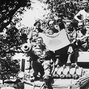 The crew of a Lee tank pose with a captured Japanese flag during the advance south of