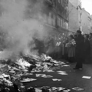 A crowd of Hungarians watch books and pamphlets from a ransacked Russian bookshop being