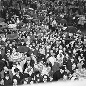 Crowds gather in the rain to catch a glimpse of Prime Minister Harold Wilson (1916 - 1995