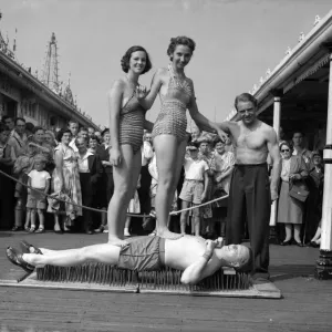 Black and white print of a man lying on a bed of nails