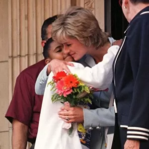 Diana, Princess of Wales, hugs a young girl who gave her flowers as she leaves Cook