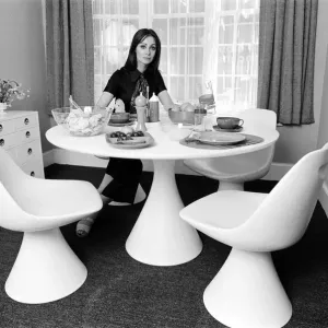 A display of modern furniture, a woman sitting in a modern dining room space