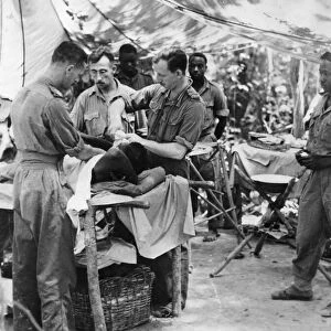 Doctors tend a wounded soldier of the 81st West African Division in an improvised