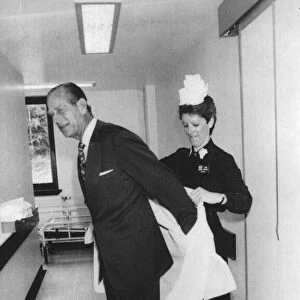 The Duke of Edinburgh. Prince Philip being helped with his protective clothing by Matron
