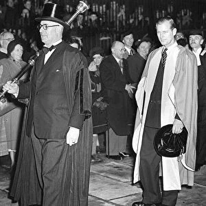 DUKE OF EDINBURGH, WEARING GOWN AND HOLDING HIS HAT, AT CAMBRIDGE UNIVERSITY WALKING IN