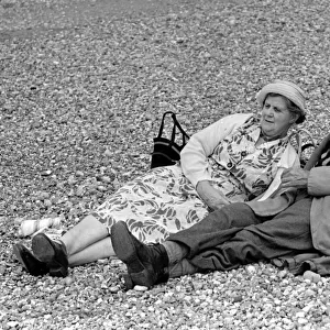 Elderly couple sunbathing on the pebble beach at Brighton July 1958