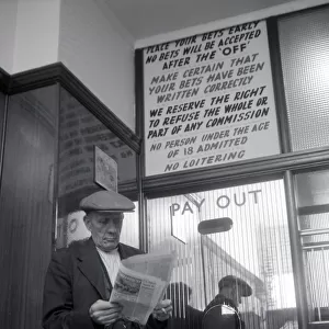 An elderly man studies the form guide inside A E Fane and Co betting shop in Islington