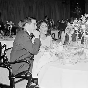 Elizabeth Taylor sitting on a dinner table with other people Liz Taylor March