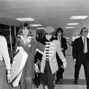 Elton John leaving Heathrow airport for a flight to Los Angeles. 9th January 1977