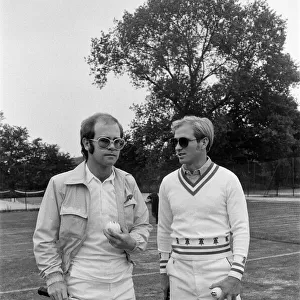 Elton John plays tennis against Larry King on an outer court at Wimbledon. 25th June 1974