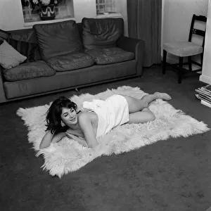 English actress Shirley Anne Field laying on sheepskin carpet dressed only in short towel