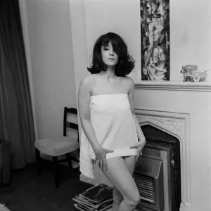 English actress Shirley Anne Field standing beside a fireplace dressed only in short