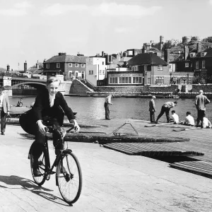 Eton schoolboy cycling along the Thames in his school uniform Circa 1955 Eton schoolboy cycling along the Thames in his school uniform Circa 1955