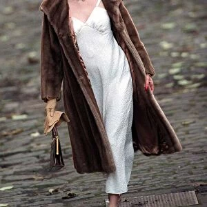 Evita Fashion Model wearing brown fur coat and hat white slip dress handbag gold