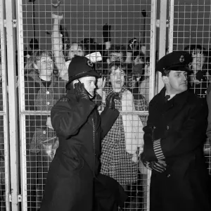 Excited female Beatles fans deafen a young policeman keeping them at bay before Excited female Beatles fans deafen a young policeman keeping them at bay before