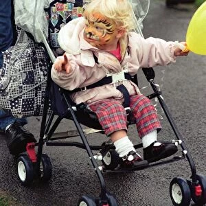 With her face painted this youngster toddled round in her pushchair during