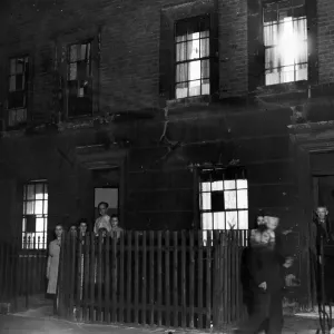 A family posing outside their home in Cab; e Street, Mile End London during a dim-out