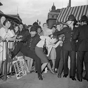 Fans of The Beatles pop group at Piccadilly Circus battle with police as they try to get