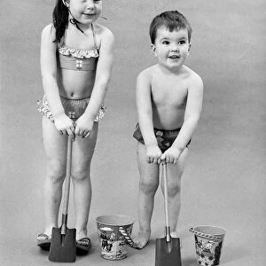 Fashion 1960s. Children play with bucket and spade in their swimwear