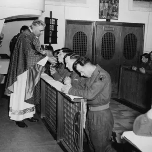 Father Devine with the British 7th Armoured Division, holds mass in a Roman Catholic Father Devine with the British 7th Armoured Division, holds mass in a Roman Catholic