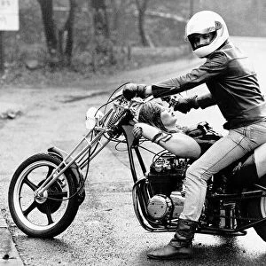 Female Model is drapped on a motorbike, whilst the driver sits rather comfortable