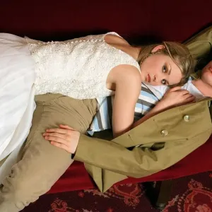 Female model lying on top of a male model along red cinema seats Female model lying on top of a male model along red cinema seats