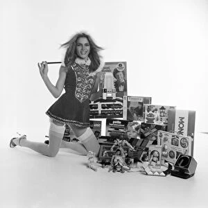A female model in a santa outfit with a selection of childrens toys for Christmas