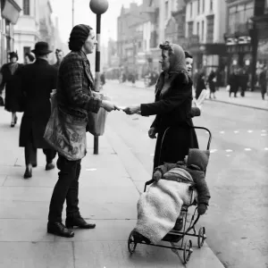 A female newspaper seller in Liverpool, selling a copy of the Daily Post to a mother in A female newspaper seller in Liverpool, selling a copy of the Daily Post to a mother in
