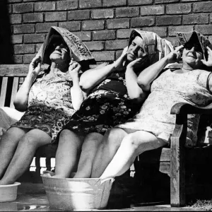 Trois vieilles dames âgées prennent place à l'extérieur au soleil, en refroidissant leurs pieds dans des seaux de. Trois vieilles dames âgées prennent place à l'extérieur au soleil, en refroidissant leurs pieds dans des seaux de.