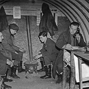 Fighter pilots of 73 Squadron RAF warm their hands on a brazier in their underground Duty
