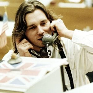 Finance Stock Exchange dealer sitting at desk Holding two telephones to each ear
