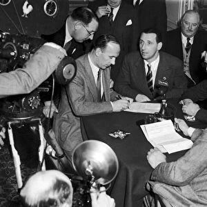 Footballer Tommy Lawton looks on as his new manager Jack Gibbons signs a contract after