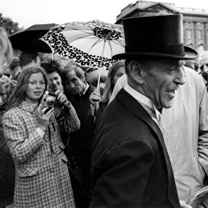 Fred Astaire returns the smiles of onlooker outside Buckingham Palace