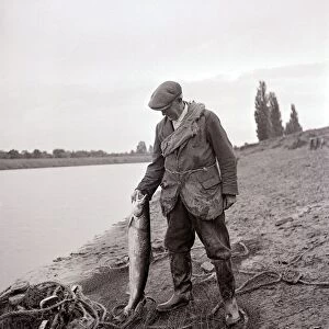 A Gamekeeper holding a Salmon, circa 1935