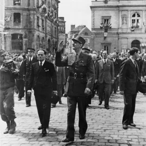 General De Gaulle waves to the wildly cheering crowds of his countrymen as he General De Gaulle waves to the wildly cheering crowds of his countrymen as he