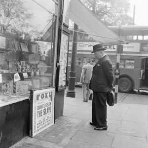 Gentleman looking at local classified and personal adverts on notice board outside shop