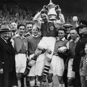 George Allison Arsenal manager (far left) looks on as Alex James Arsenal captain holds George Allison Arsenal manager (far left) looks on as Alex James Arsenal captain holds