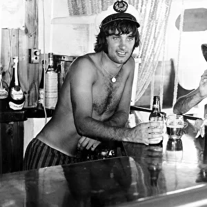 George Best Footballer in a sailors cap behind the bar in his favourite pub in Palma Nora