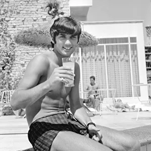 George Best relaxing on holiday with a drink and sitting on the edge of a swimming pool