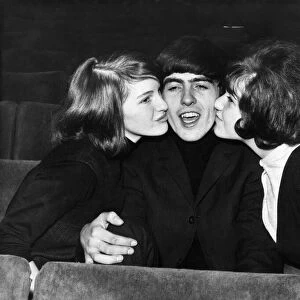 George Harrison of The Beatles is kissed by two female fans